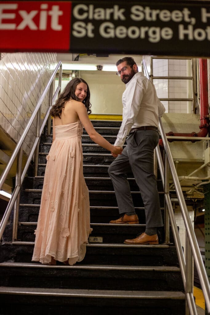 An engaged couple walk up the steps of a Brooklyn subway.