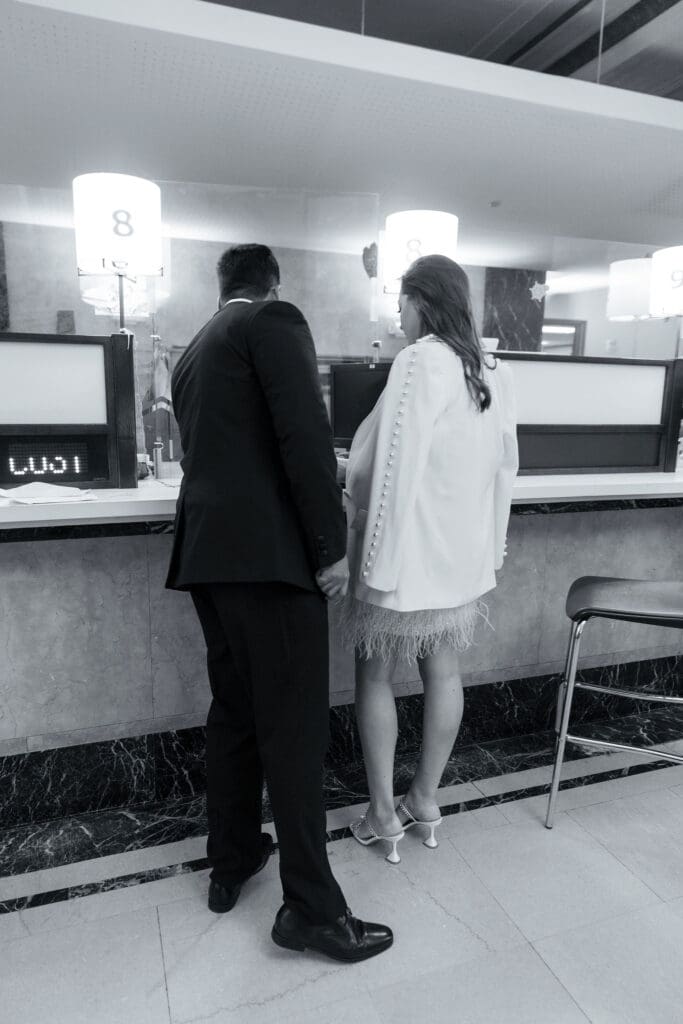 Photo from behind of a couple signing paperwork before getting married at NYC City Hall. Black and White Image.