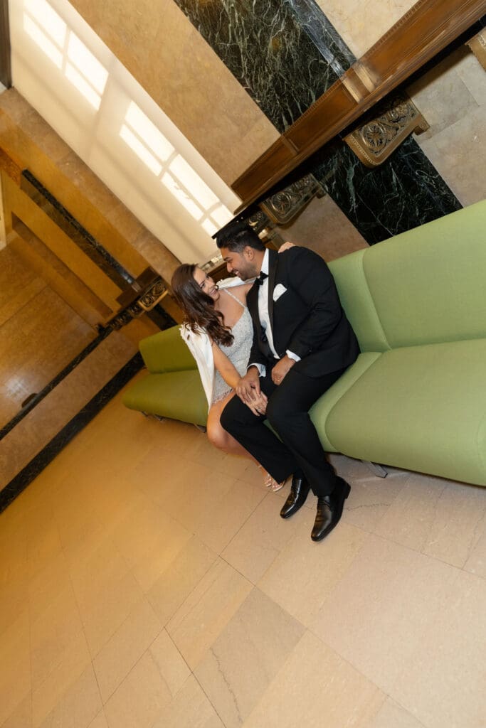 Newlywed couple pose at the green couches after getting married at NYC City Hall.