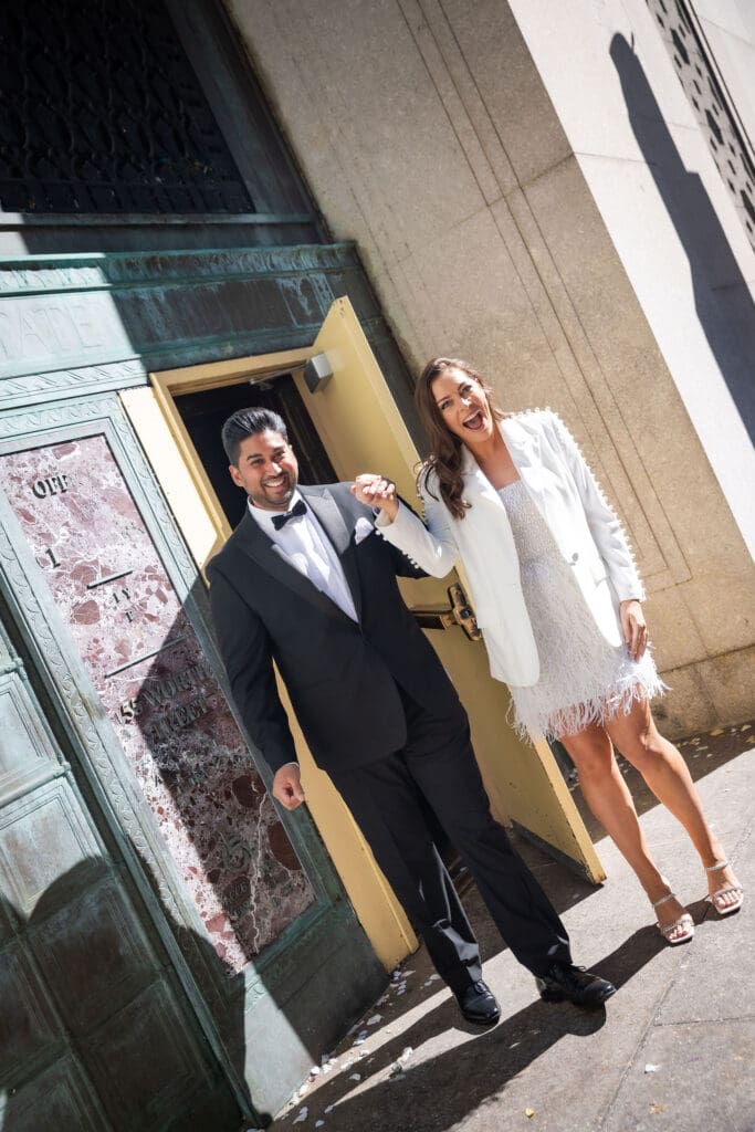 Newlywed couple celebrate at the exit door after getting married at NYC City Hall.