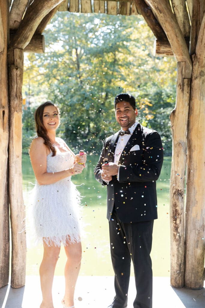 Newlywed couple pop confetti at Wagner Cove in Central Park NYC after getting married at City Hall.