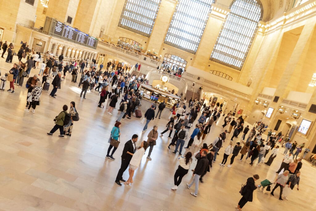 Fancy Newlywed UK couple pose inside Grand Central Station in NYC after getting married at City Hall, as people wander around them.