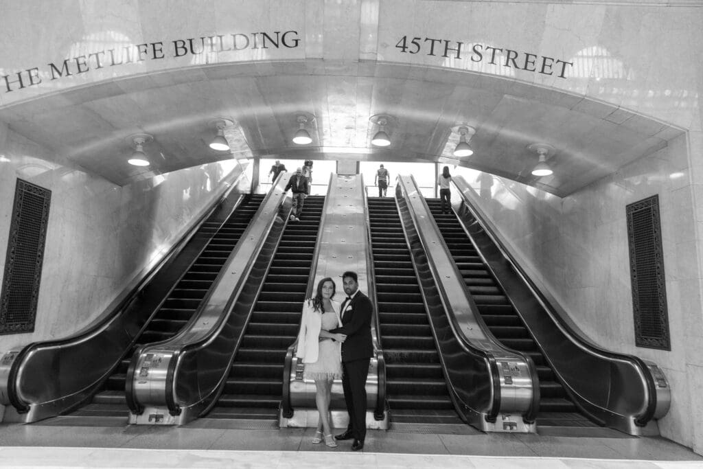 Fancy Newlywed UK couple pose near main escalators inside Grand Central Station in NYC after getting married at City Hall. Black and White Image.