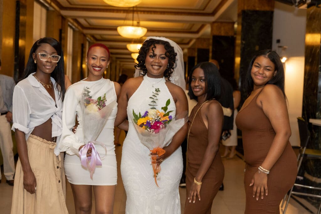 Two brides smile with their friends while waiting to get married at NYC City Hall.
