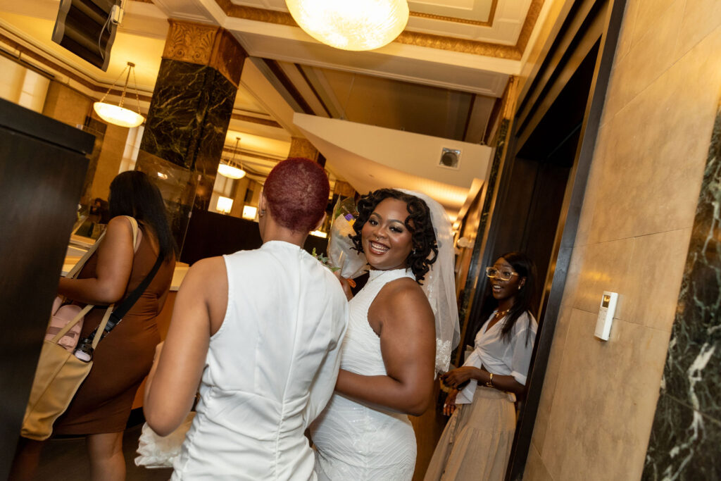 A bride smiles at the camera amidst all her friends after getting married at NYC' City Hall.