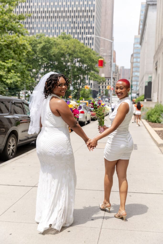 Two brides walk down the street in NYC after getting married at City Hall.