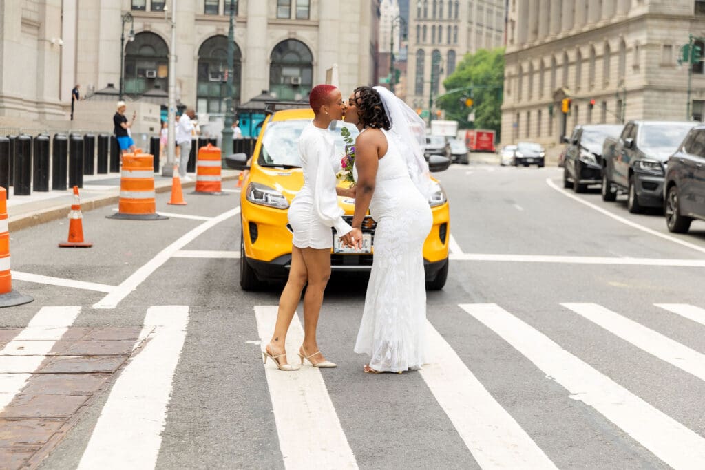 Two brides kiss in front of a NYC taxi after getting married at City Hall.