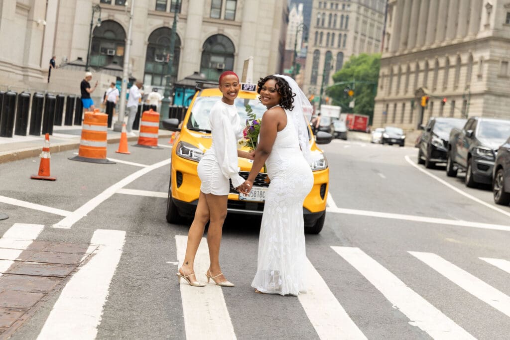 Two brides in front of a NYC taxi after getting married at City Hall.