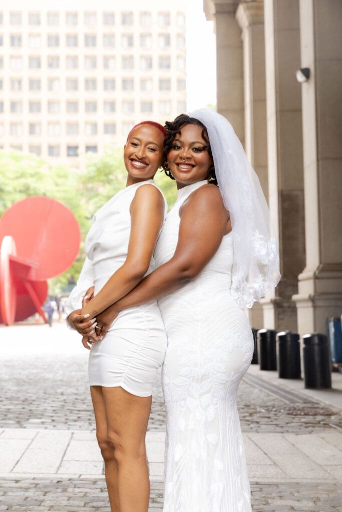 Two brides embrace in NYC after getting married at City Hall.