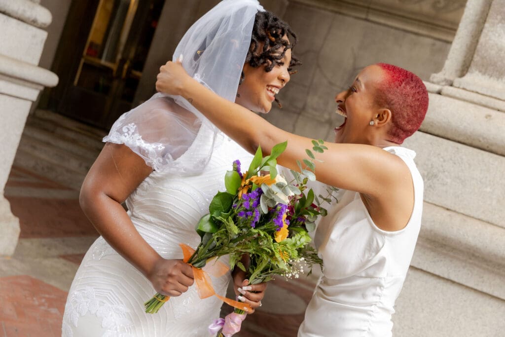 Two brides laughing in NYC after getting married at City Hall.