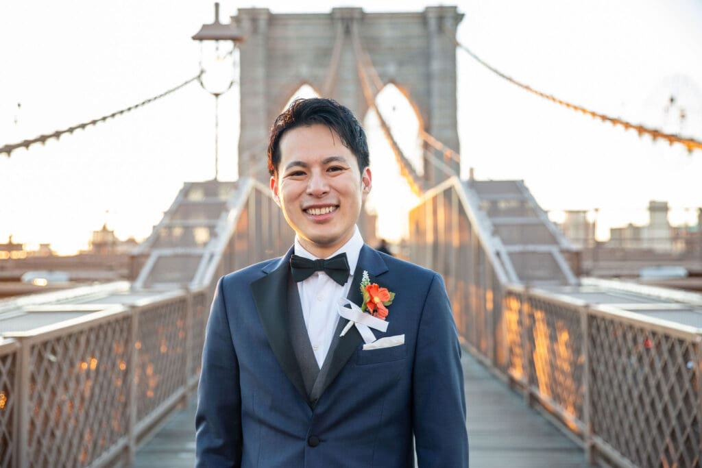 Groom poses at the Brooklyn Bridge in NYC.