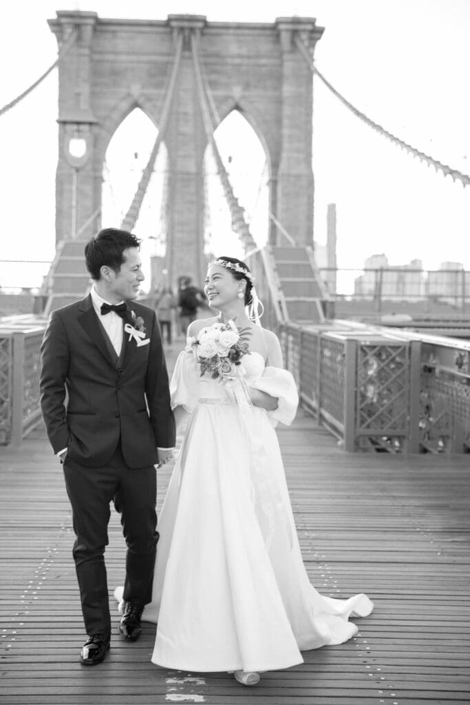 Newlyweds laugh and walk around at the Brooklyn Bridge in NYC. Black and White Image.