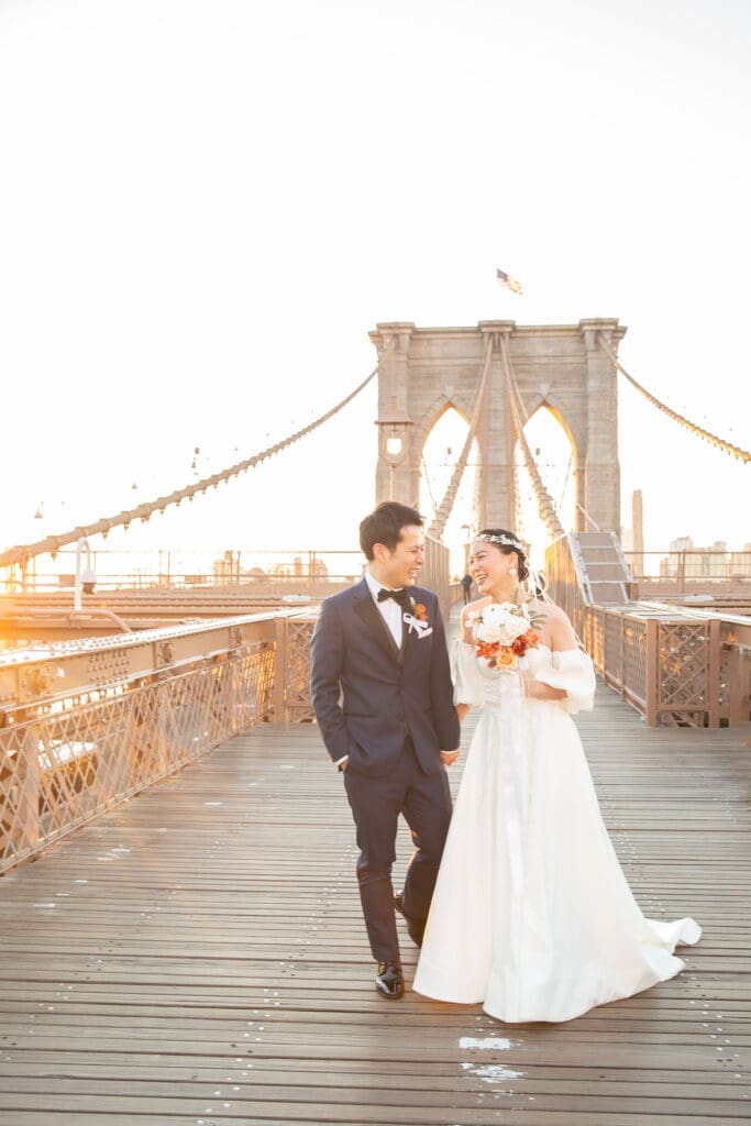 Newlyweds laugh and walk around at the Brooklyn Bridge in NYC.