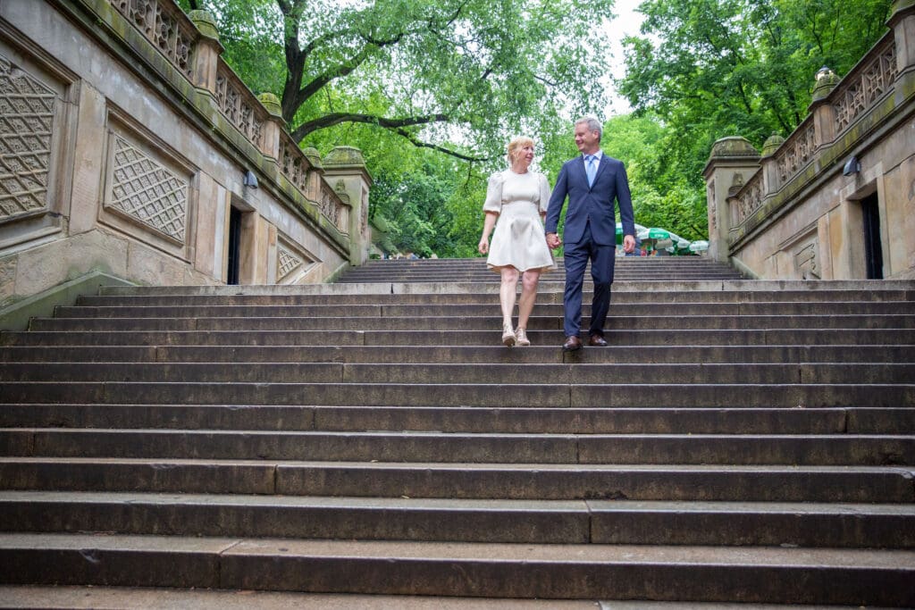 NYC Elopement in Central Park after after ceremony at the Norwegian Seamen's Church. Bride and groom walk down the steps near Bethesda Terrace.