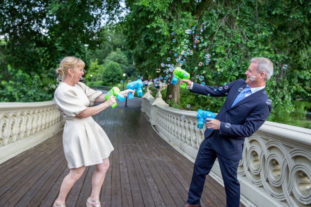 NYC Elopement in Central Park after after ceremony at the Norwegian Seamen's Church. Bride and groom blow bubbles at each other.