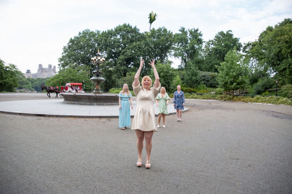 NYC Elopement in Central Park after after ceremony at the Norwegian Seamen's Church. Bride throws the bouquet near Cherry Hill.