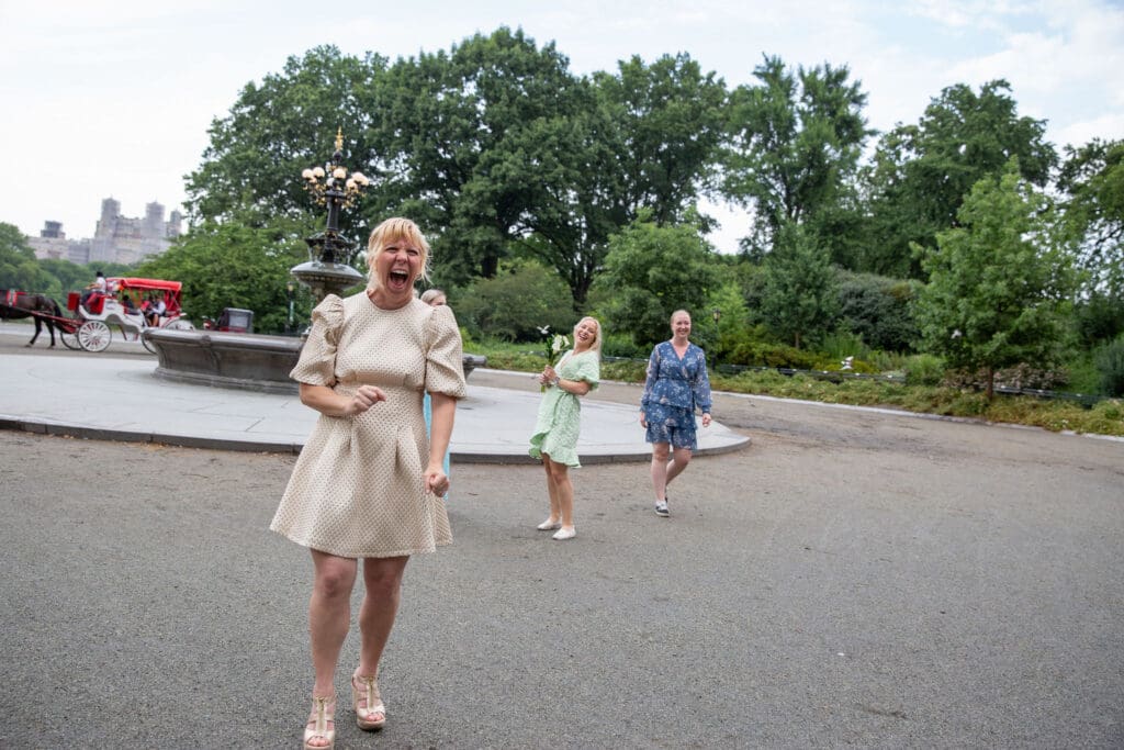 NYC Elopement in Central Park after after ceremony at the Norwegian Seamen's Church. Bride laughs after throwing the bouquet near Cherry Hill.