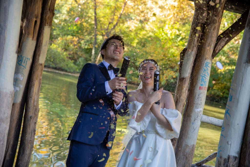 Newlyweds pop confetti at Wagner Cove in NYC's Central Park.