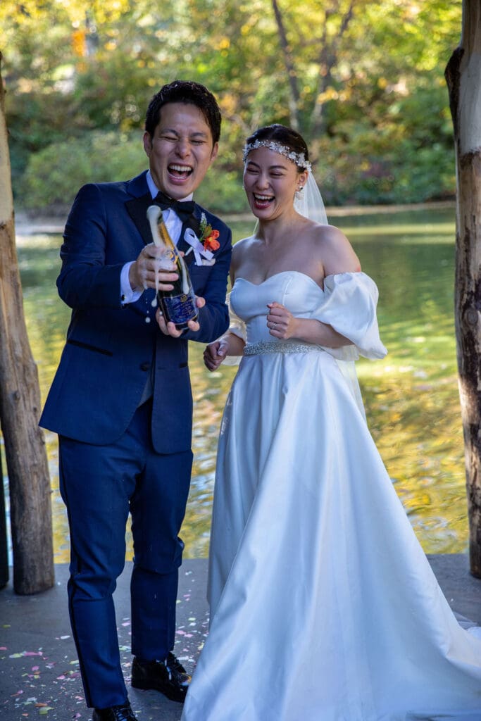 Newlyweds pop champagne at Wagner Cove in NYC's Central Park.