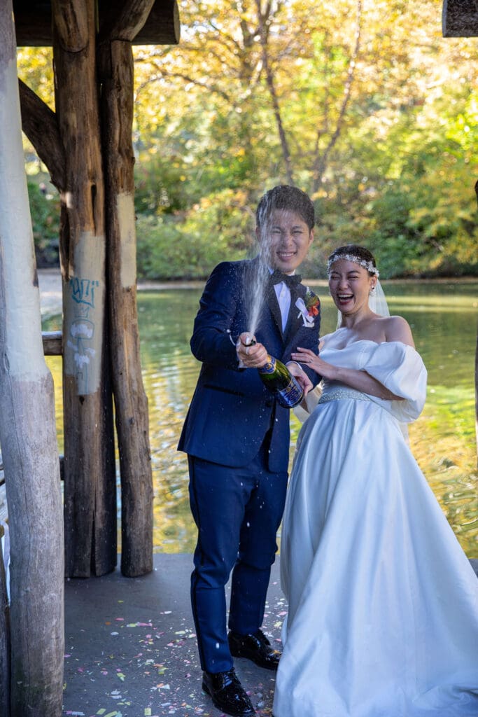 Newlyweds pop champagne at Wagner Cove in NYC's Central Park.