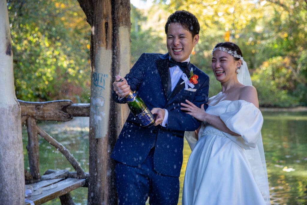 Newlyweds pop champagne at Wagner Cove in NYC's Central Park.