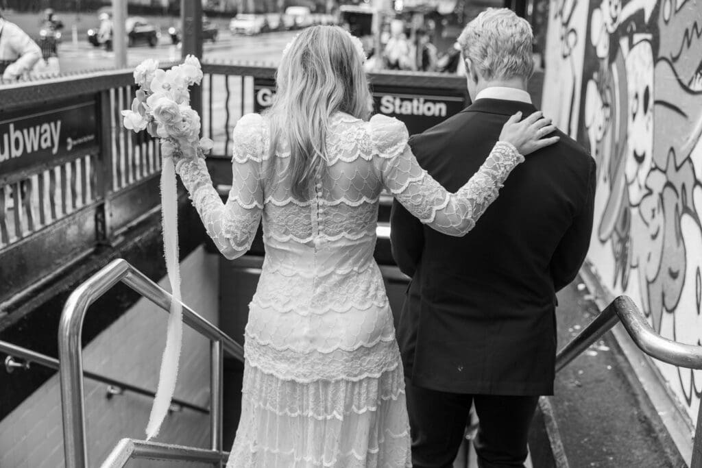 Newlyweds take wedding portraits walk down steps of Grand St Subway station in Chinatown NYC.
