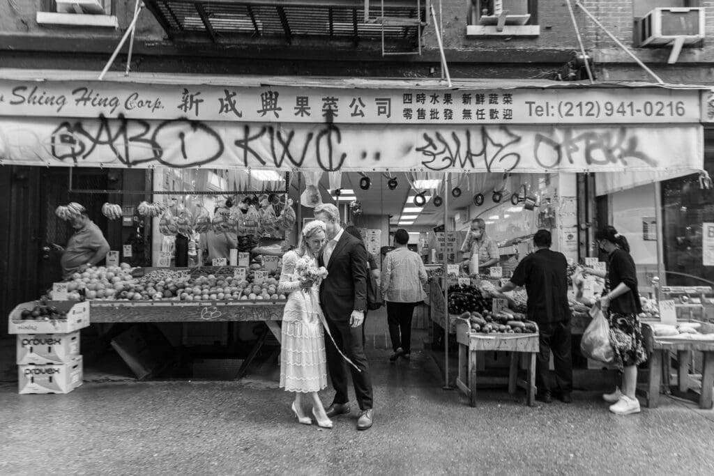 Newlyweds take wedding portraits along Mott St in Chinatown NYC. Black and White Image.