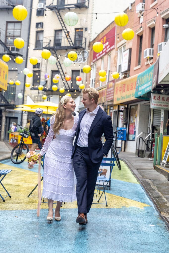 Newlyweds take wedding portraits in Chinatown NYC on Doyers Street with lanterns in background.