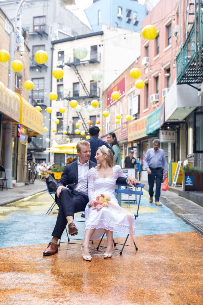 Newlyweds take wedding portraits in Chinatown NYC on Doyers Street with lanterns in background.