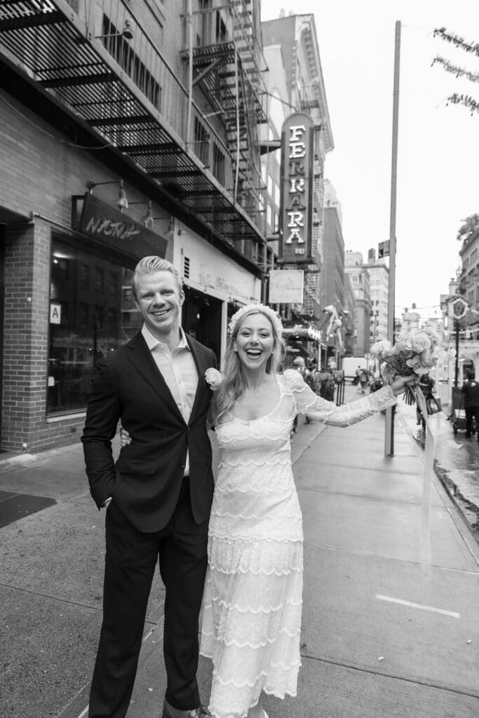 Newlyweds laugh during wedding portraits in Little Italy NYC with Ferrara's in the background.