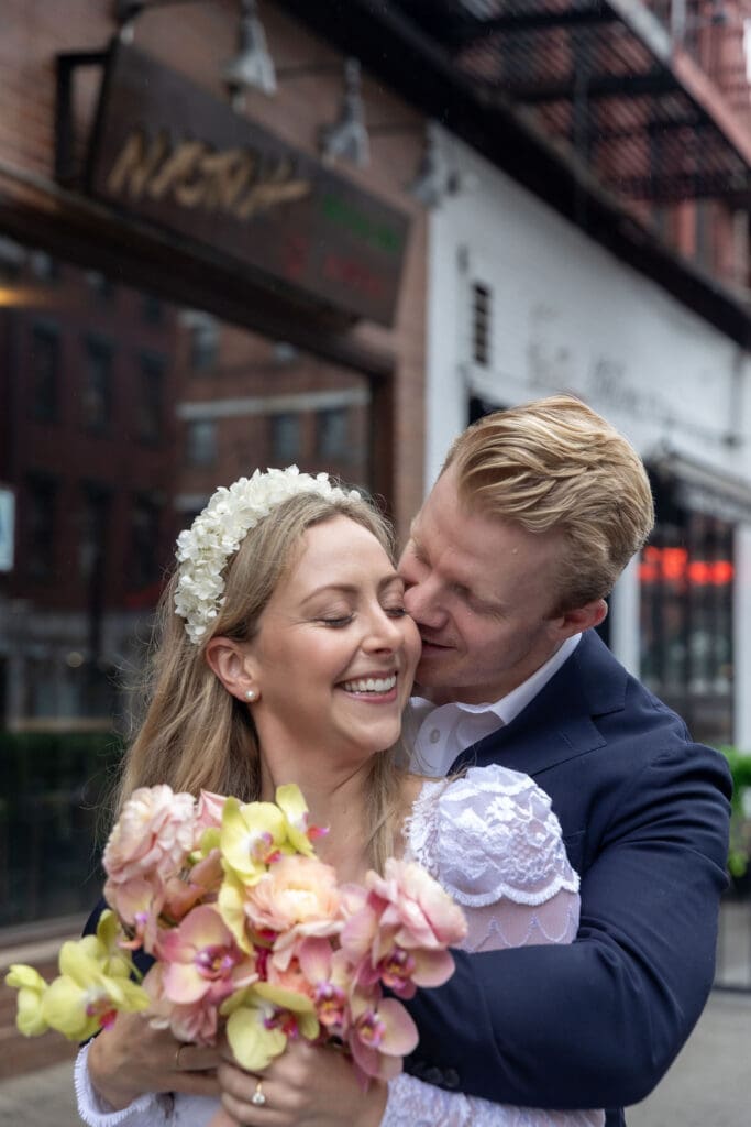 Newlyweds share a sweet moment during wedding portraits in Little Italy NYC with Ferrara's in the background.