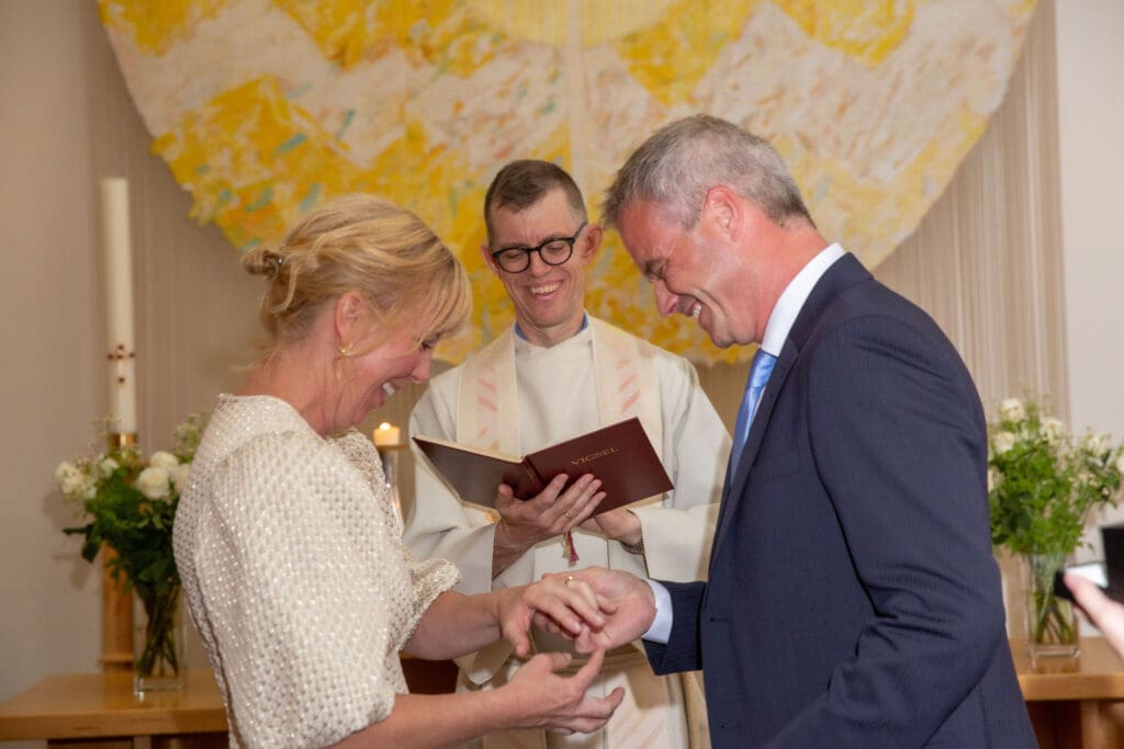 NYC Elopement at the Norwegian Seamen's Church. Bride and Groom smile with minister during ceremony.