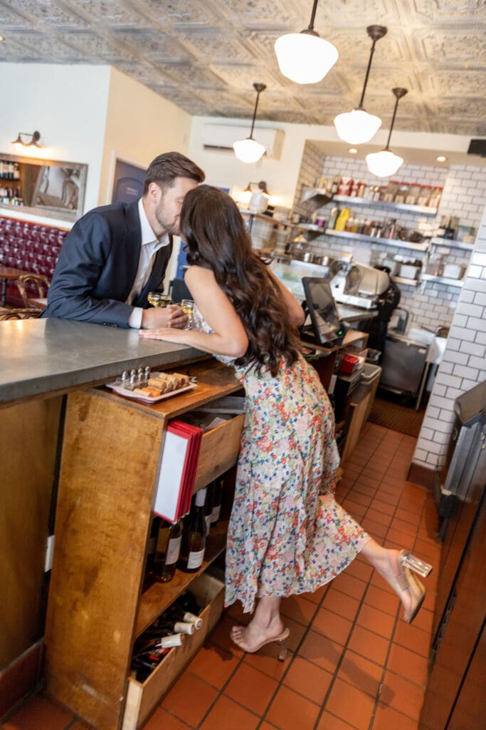 Engaged couple kiss behind the bar at Vin Sur Vingt on Manhattan's Upper West Side.
