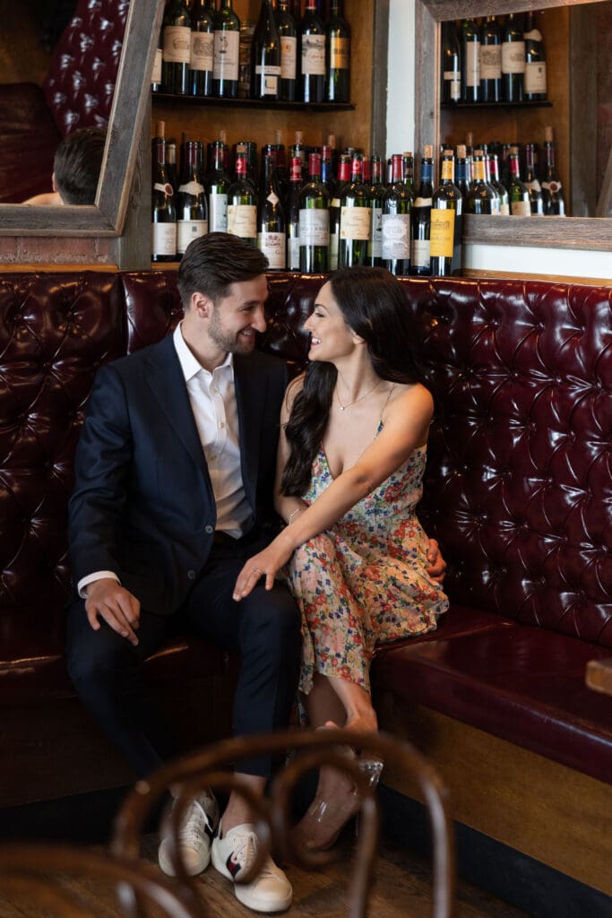 Engaged couple smiling at a bench at Vin Sur Vingt on Manhattan's Upper West Side.