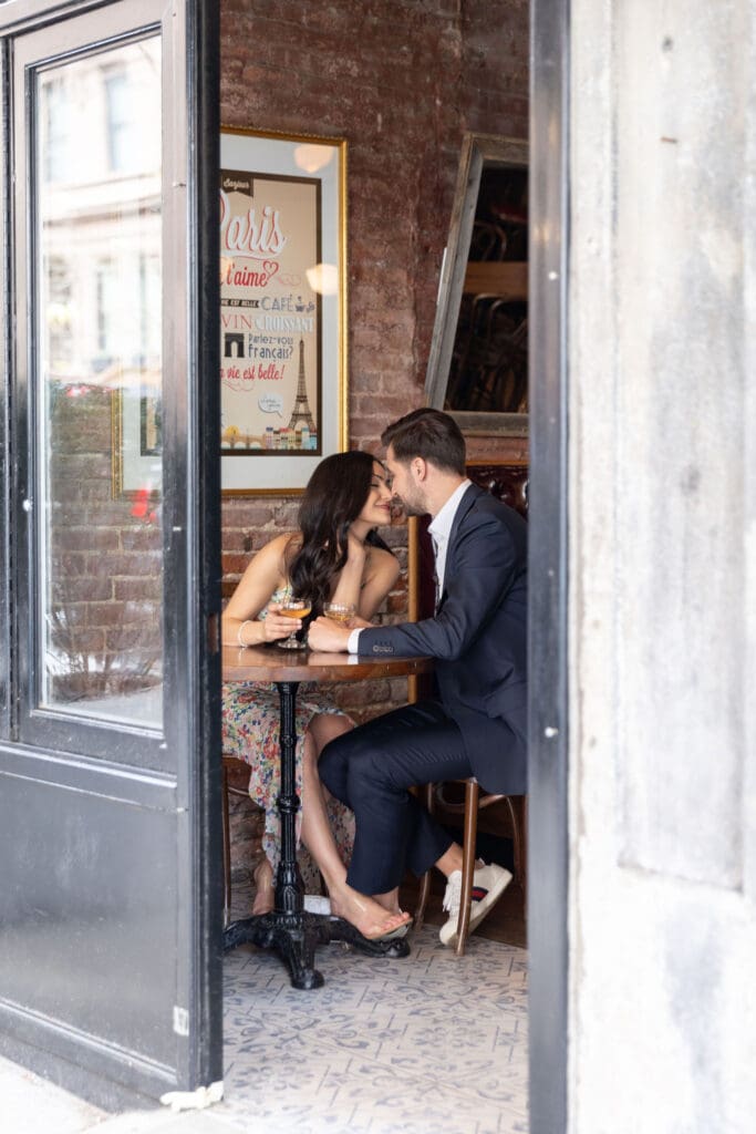 Photo taken through a window of an engaged couple kissing at Vin Sur Vingt on Manhattan's Upper West Side.