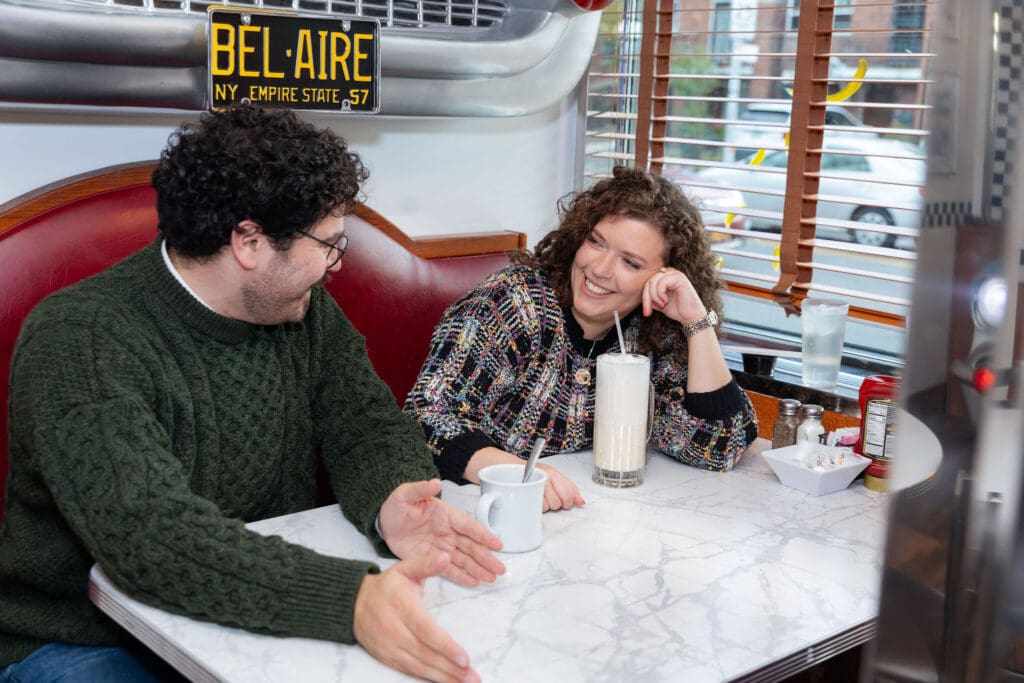 Engaged couple enjoy milkshakes in at Bel-Aire Diner in Astoria, Queens during their casual pre-wedding portrait session in NYC.