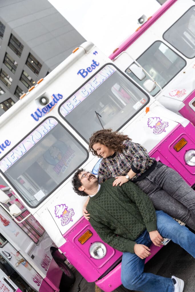 Engaged couple pose near ice cream trucks in Astoria, Queens for their fall engagement session.