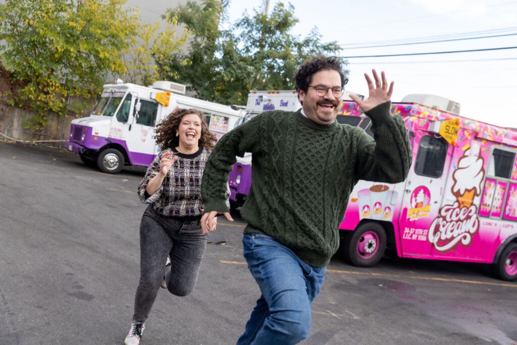 Engaged couple pose near ice cream trucks in Astoria, Queens for their fall engagement session.