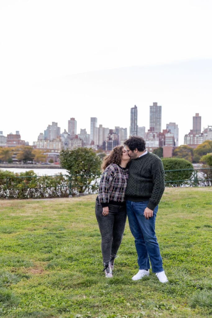 Engaged couple kiss in Socrates Sculpture Park in Astoria, Queens for their fall engagement session.